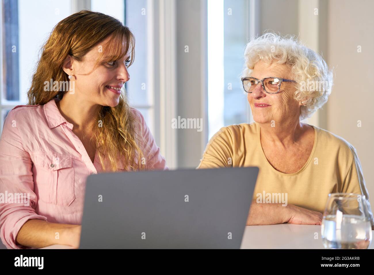 Une jeune femme et une mère âgée ensemble à la table en utilisant un ordinateur portable à la maison Banque D'Images