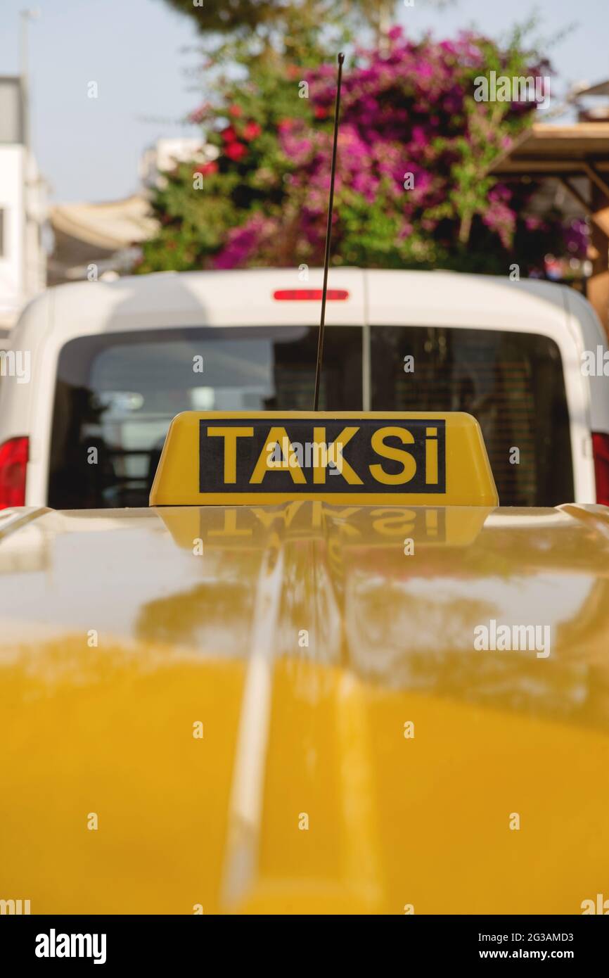 Panneau jaune vif pour le taxi sur le toit d'une voiture jaune par une journée ensoleillée. Banque D'Images