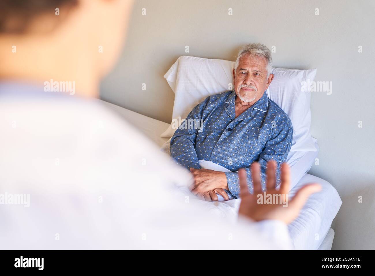 Le patient âgé au lit à l'hôpital écoute son médecin pendant les rondes comme une consultation Banque D'Images