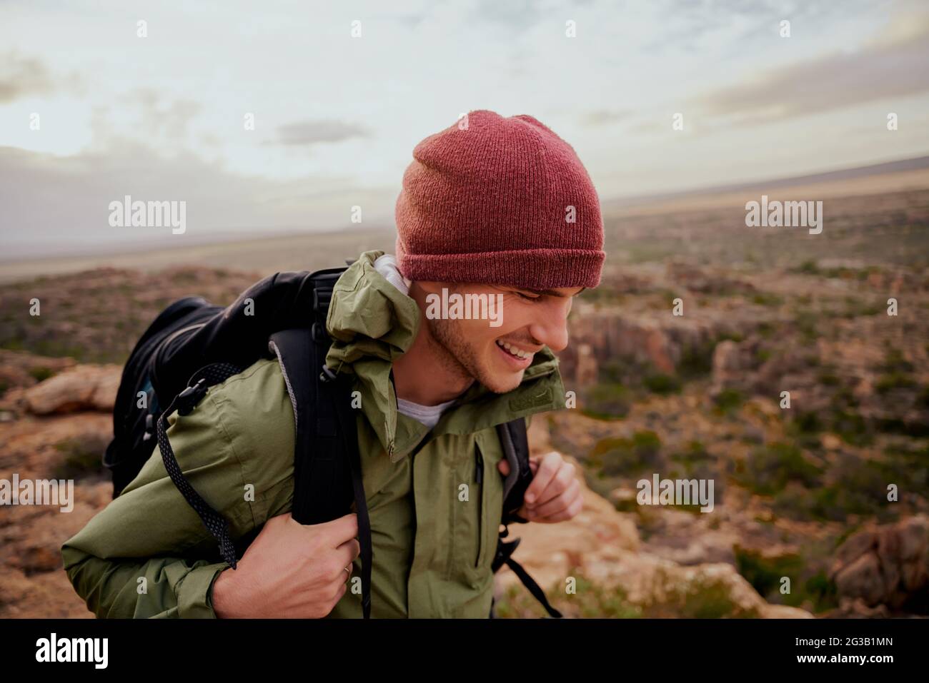 Joyeux randonneur masculin portant un sac à dos escalade sentier de montagne portant un chapeau dans des vêtements de sport Banque D'Images