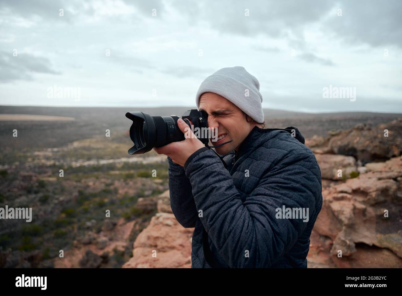 Portrait de jeune randonneur mâle prenant des photos de montagnes et magnifique lever de soleil avec un appareil photo professionnel Banque D'Images
