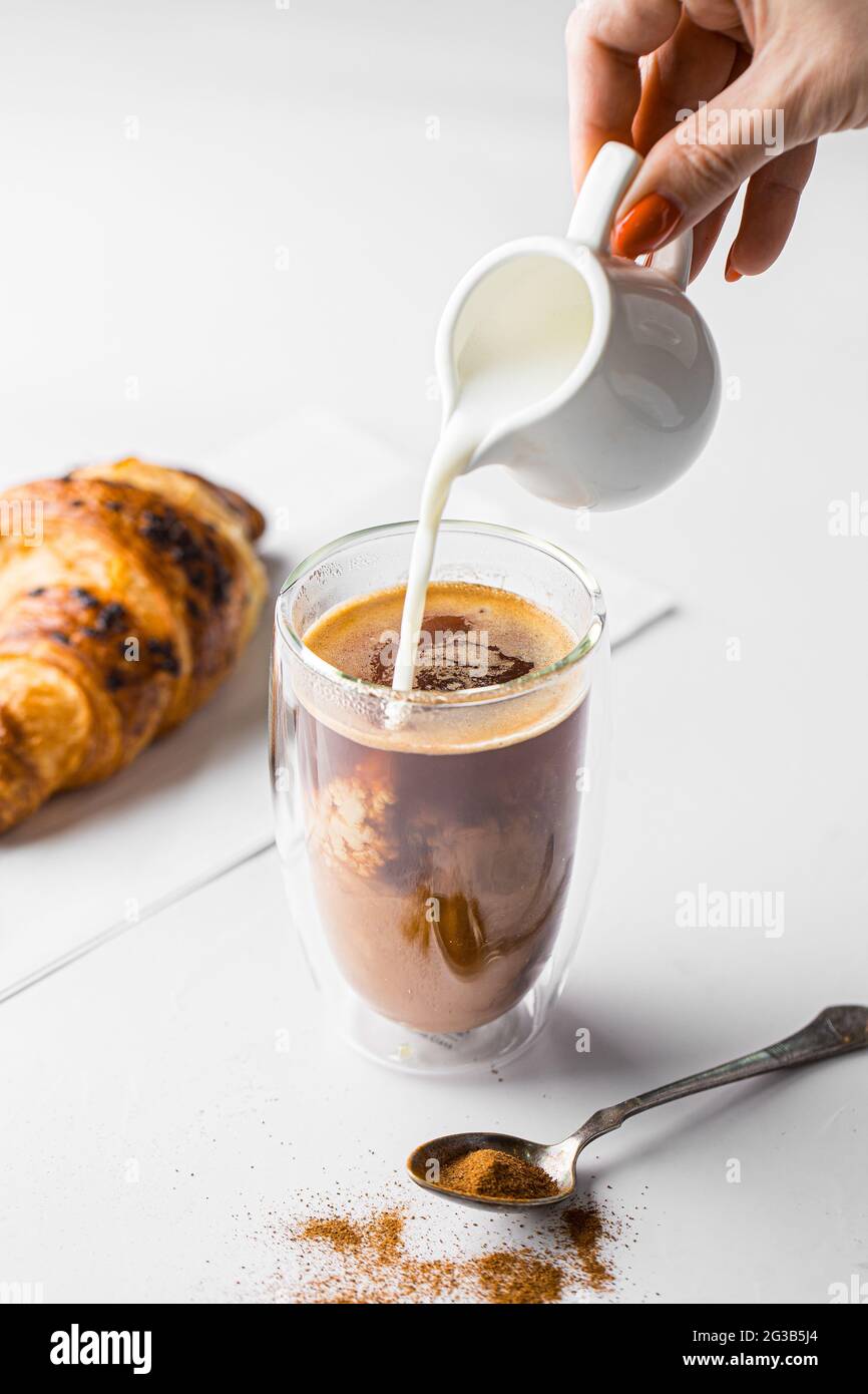 Verser le lait dans un verre de Latte à café Banque D'Images