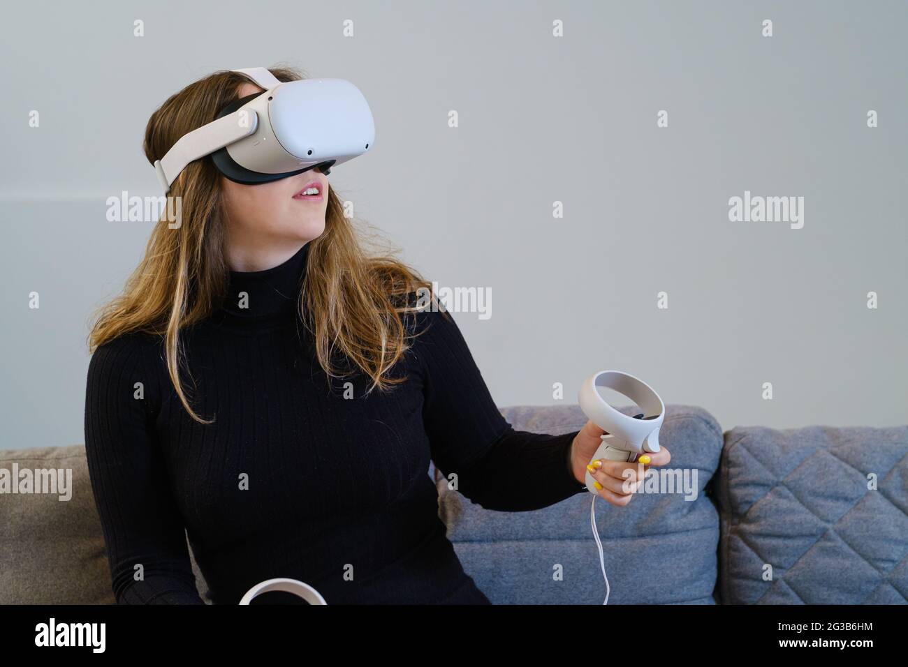 ANVERS, BELGIQUE - 08 avril 2021 : une jeune femme essaie la quête 2 d'Oculus pour une expérience virtuelle. Assis dans un canapé, avec un dessus noir. Banque D'Images