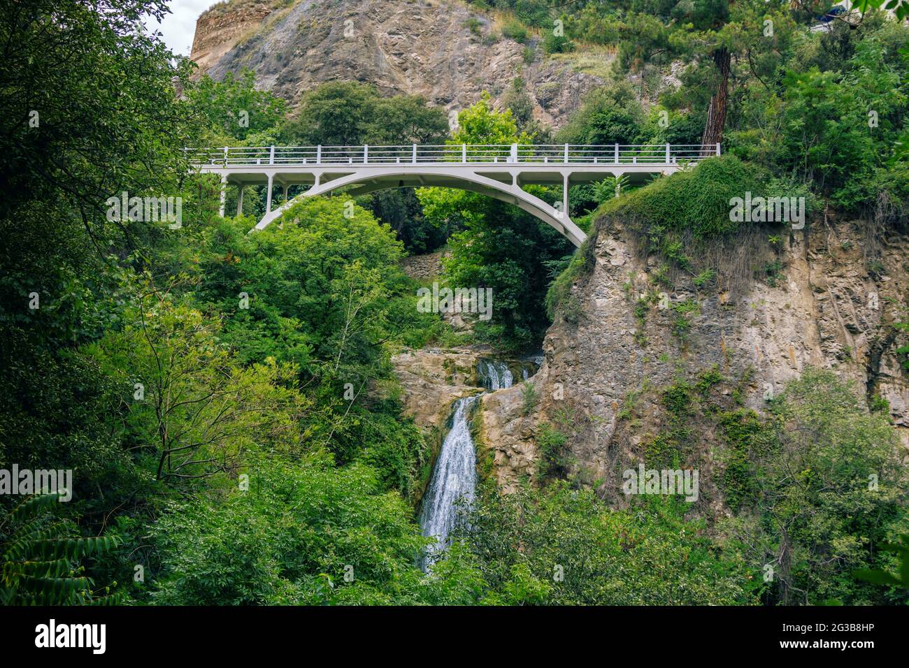 Magnifique paysage d'été du jardin botanique – Tbilissi, Géorgie – feuillage luxuriant, montagnes, pont et chute d'eau. Banque D'Images