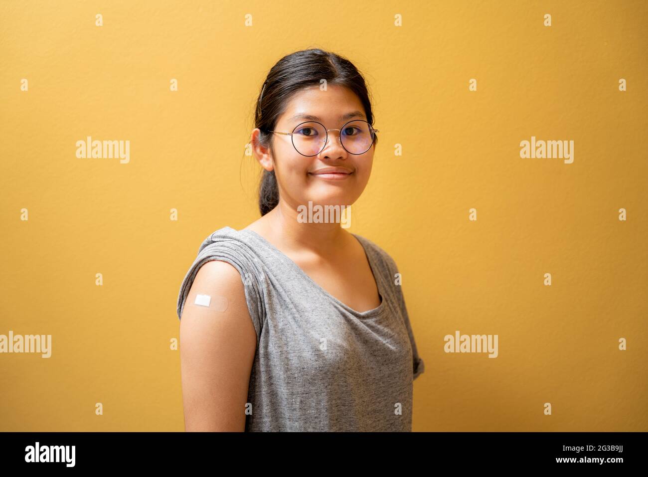 Portrait d'une jeune fille asiatique heureuse après avoir reçu l'injection de vaccin Covid-19 et montrant le bandage sur son bras, fille thaïlandaise, vaccinée Banque D'Images