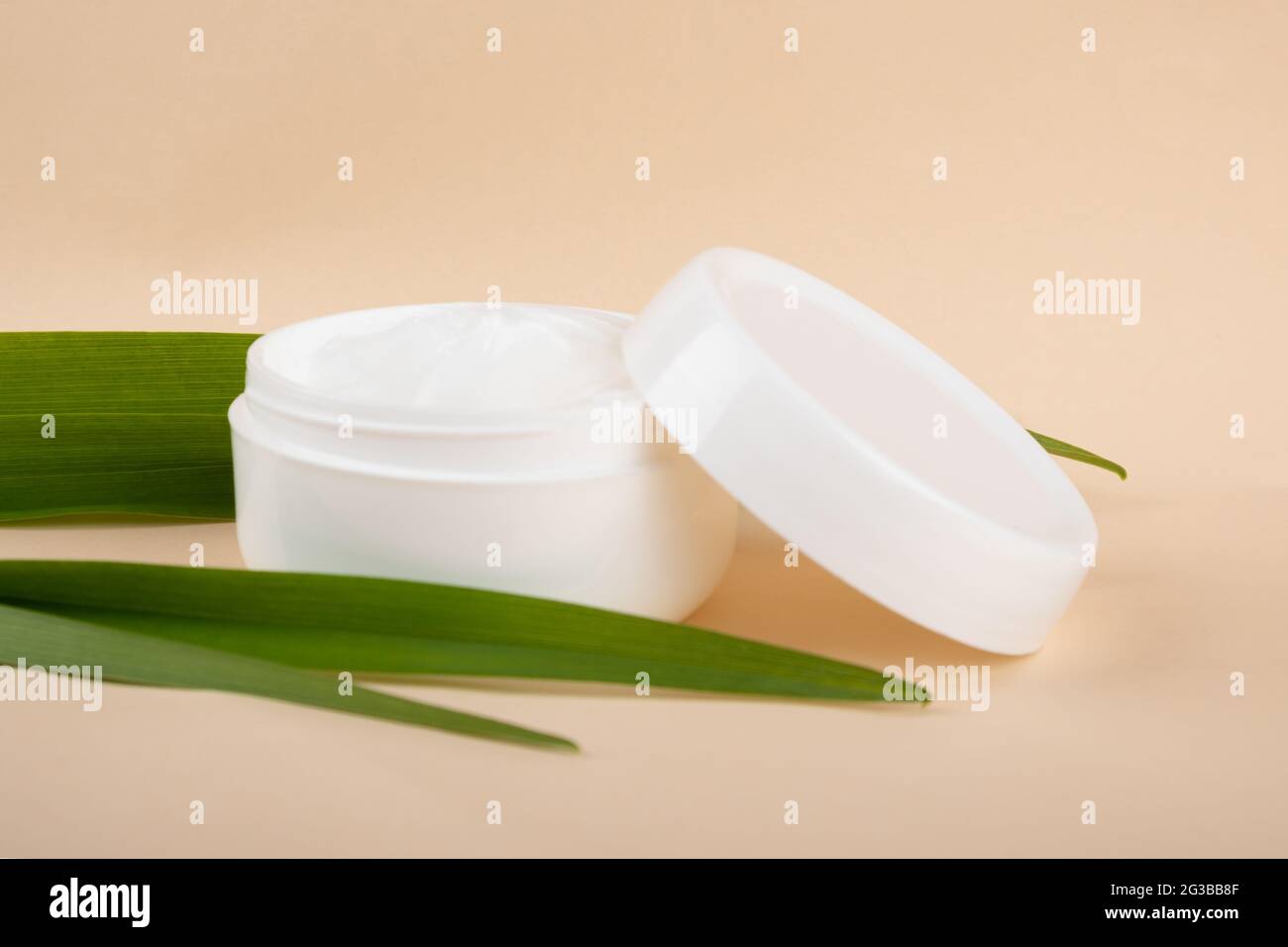 crème cosmétique et feuille verte sur fond beige. soins de la peau. Banque D'Images