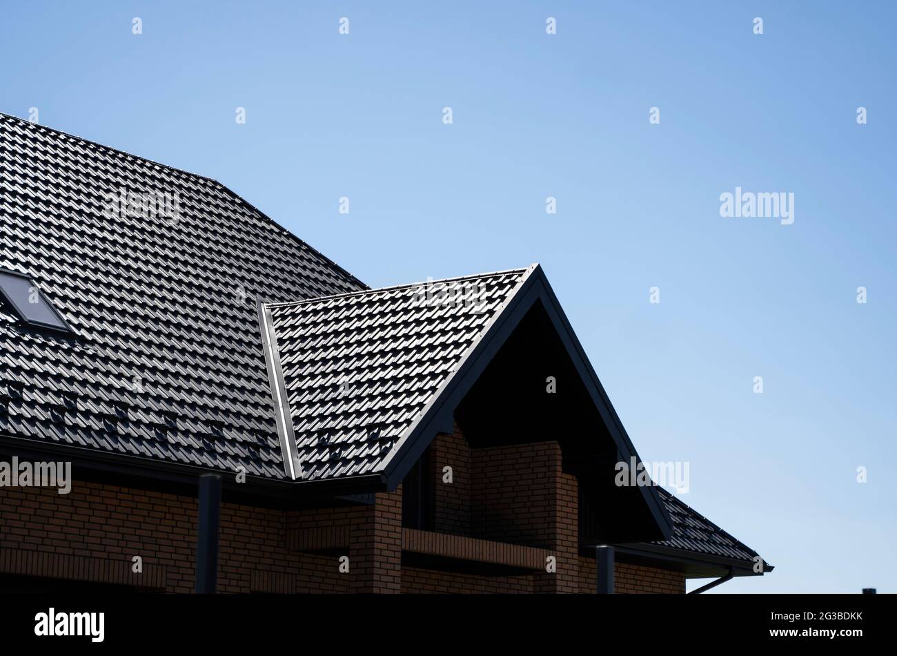 Toit en métal ondulé brun installé sur une maison moderne avec des fenêtres mansardées. Le toit de tôle ondulée. Toiture de profil métallique ondulée Banque D'Images