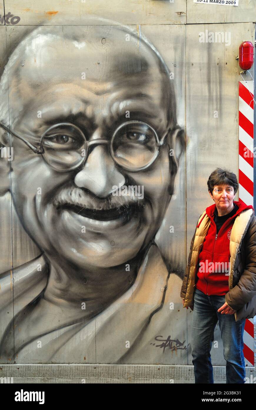 Padoue, une femme pose près d'une peinture murale représentant Gandhi. Banque D'Images