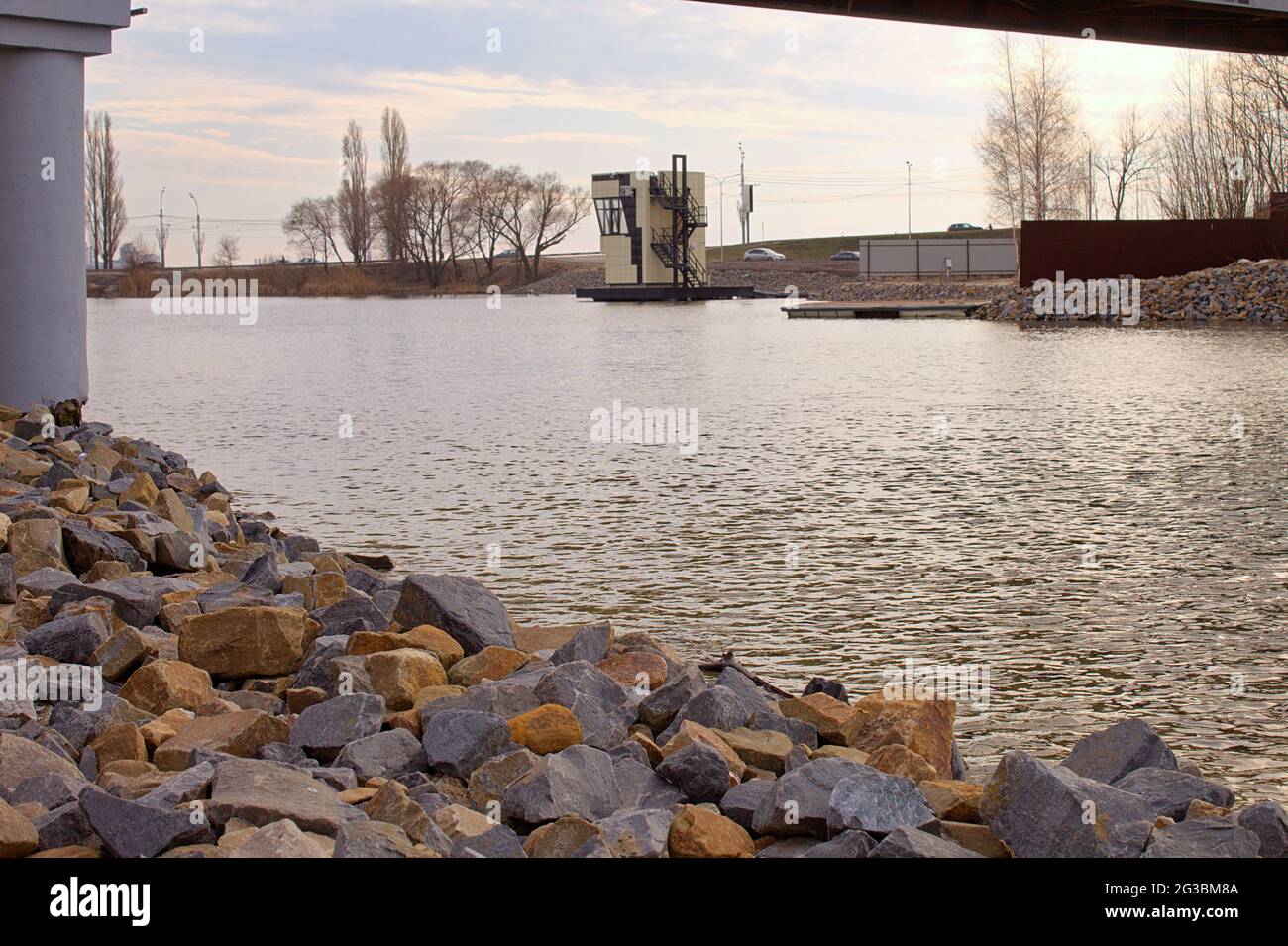 Brise-lames sur la rive de la rivière. Paysage avec pierres, arbres et pont Banque D'Images