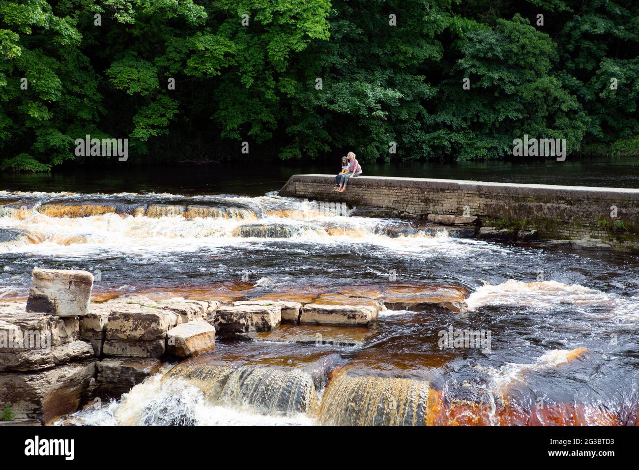 Une mère et une fille s'assoient en regardant les chutes de Richmond. Une série de cascades le long de la rivière Swale à Richmond dans le North Yorkshire. Banque D'Images