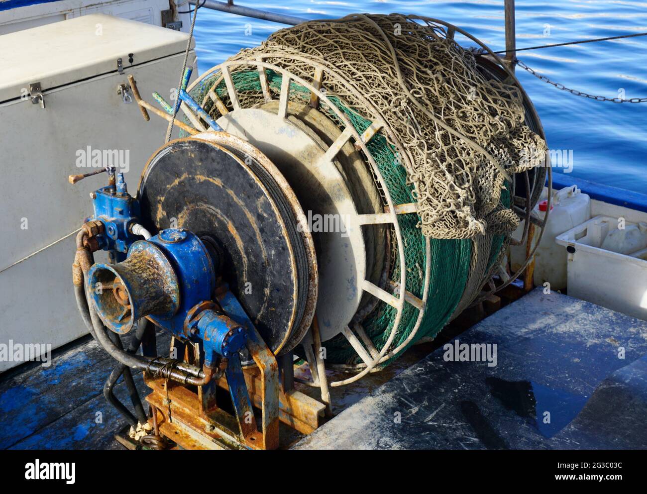 Vieilles et rouillées treuil cabestan de trawler bateau de pêche avec filet de pêche sur elle. L'équipement pour la pêche et le chalutage de fond Banque D'Images