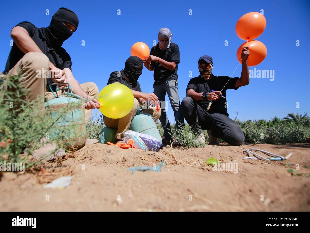 Gaza, Palestine. 15 juin 2021. Les Palestiniens masqués préparent des ballons incendiaires à lancer de la bande de Gaza vers Israël. Des militants palestiniens lancent des ballons incendiaires depuis la bande de Gaza vers Israël pour protester contre la marche du drapeau qui se déroule actuellement à Jérusalem-est et les inquiétudes d'une nouvelle flambée de violence alors que quelque 5,000 nationalistes de droite doivent défiler dans la vieille ville de Jérusalem en signe de drapeau bleu et blanc d'Israël. Des ballons incendiaires de Gaza ont brûlé des terres agricoles dans au moins 13 endroits différents, rapporte les médias israéliens. Crédit : SOPA Images Limited/Alamy Live News Banque D'Images