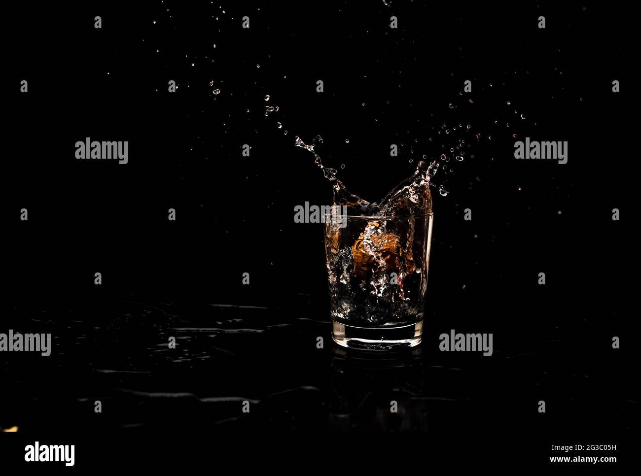 Mouvement de projection d'eau haute résolution d'un verre d'eau propre conservé sur un plateau de service en bois, isolé sur fond noir Banque D'Images