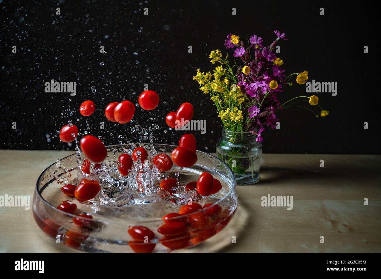 Gros plan de tomatos rouge de prune de bébé biologique frais (tomate de bébé, tomate de cerise) le groupe tombant sur le bol d'eau avec l'eau splash copyspace fleur backgro Banque D'Images