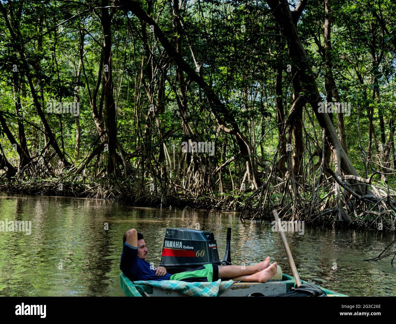 Un résident de l'île Montecristo fait une pause sur son bateau le long des canaux à côté des mangroves Banque D'Images