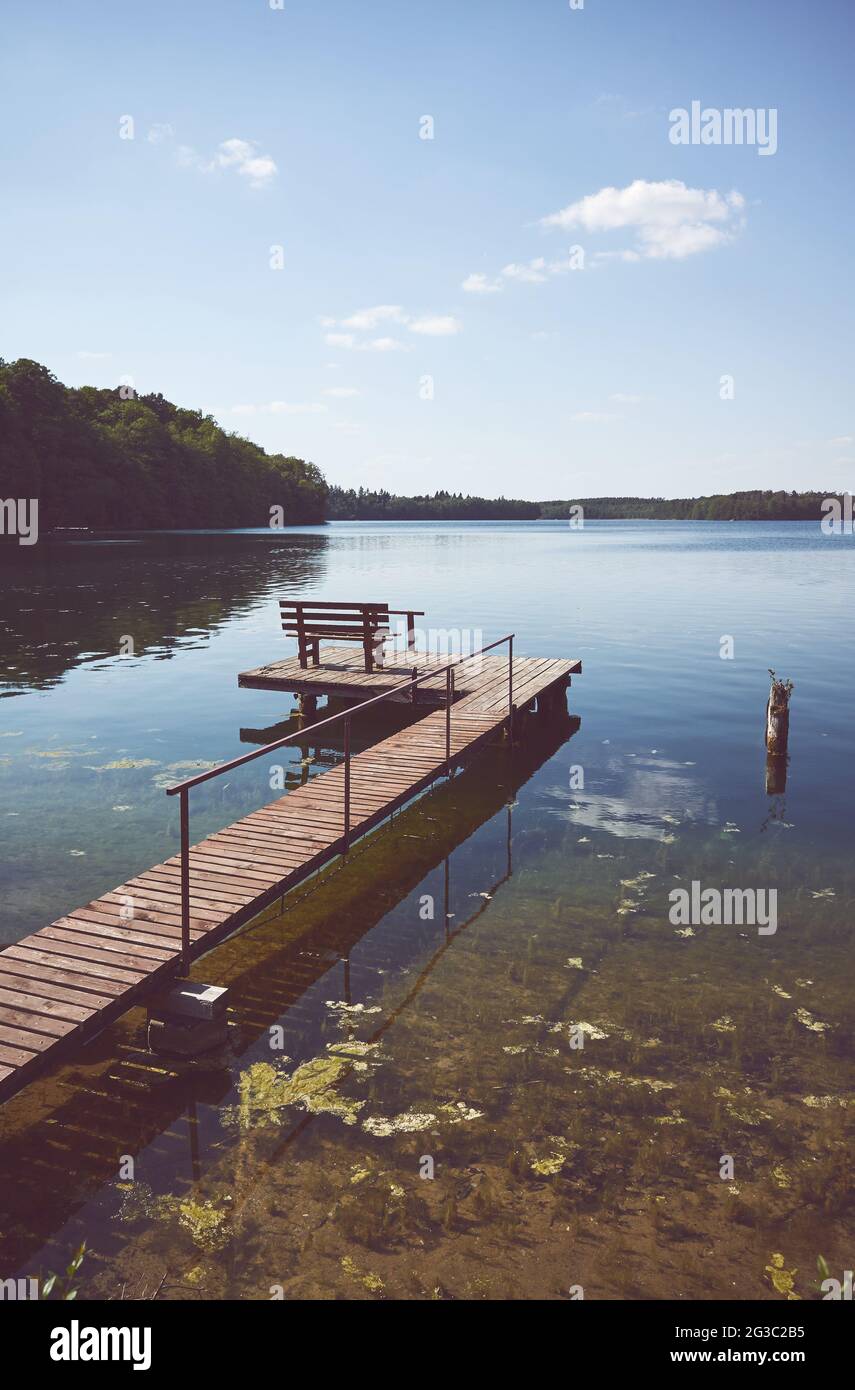 Plate-forme de pêche et de loisirs en bois au lac Lipie par une journée ensoleillée, virage de couleur appliqué, Pologne. Banque D'Images