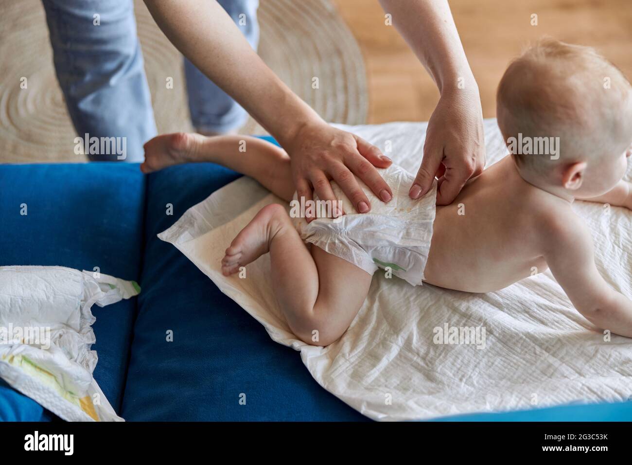 Mère mettant la couche sur bébé nouveau-né sur le canapé Banque D'Images