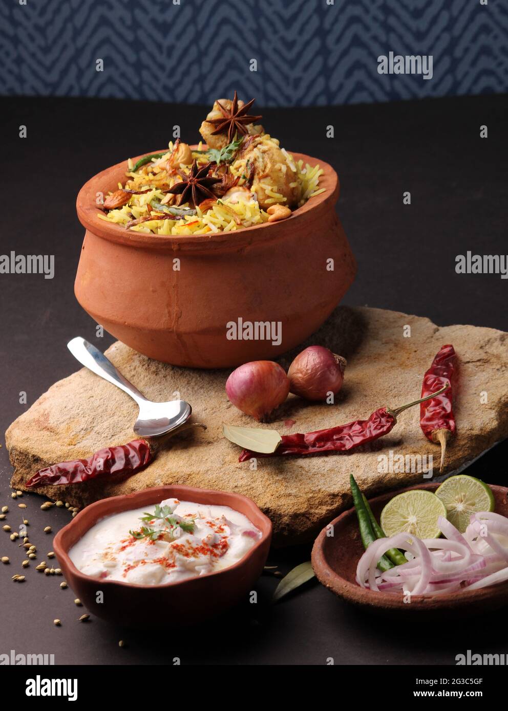 Poulet épicé dum biryani dans un handi traditionnel ou une casserole d'argile. Servi avec raita d'oignon Banque D'Images