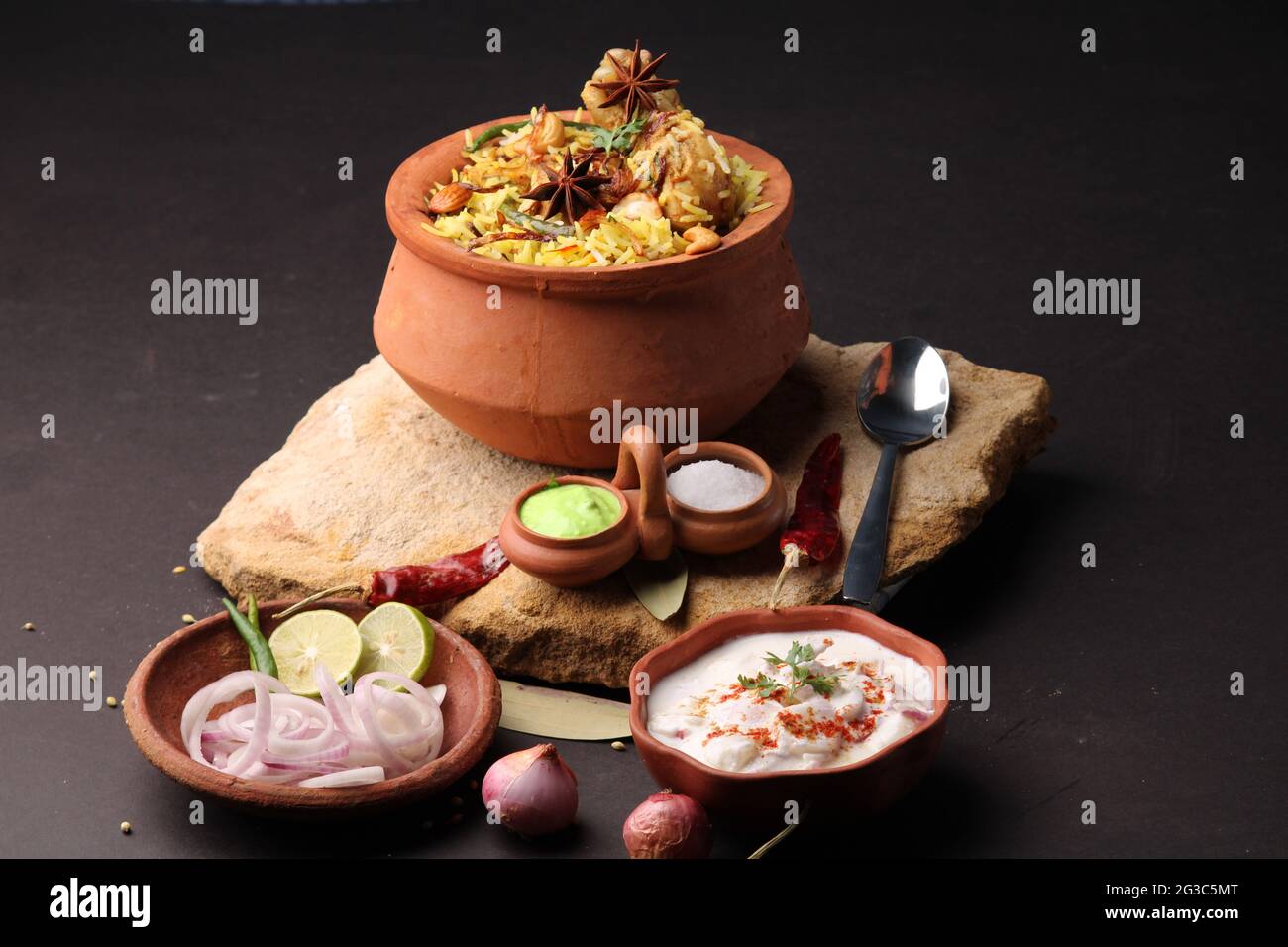 Poulet épicé dum biryani dans un handi traditionnel ou une casserole d'argile. Servi avec raita d'oignon Banque D'Images