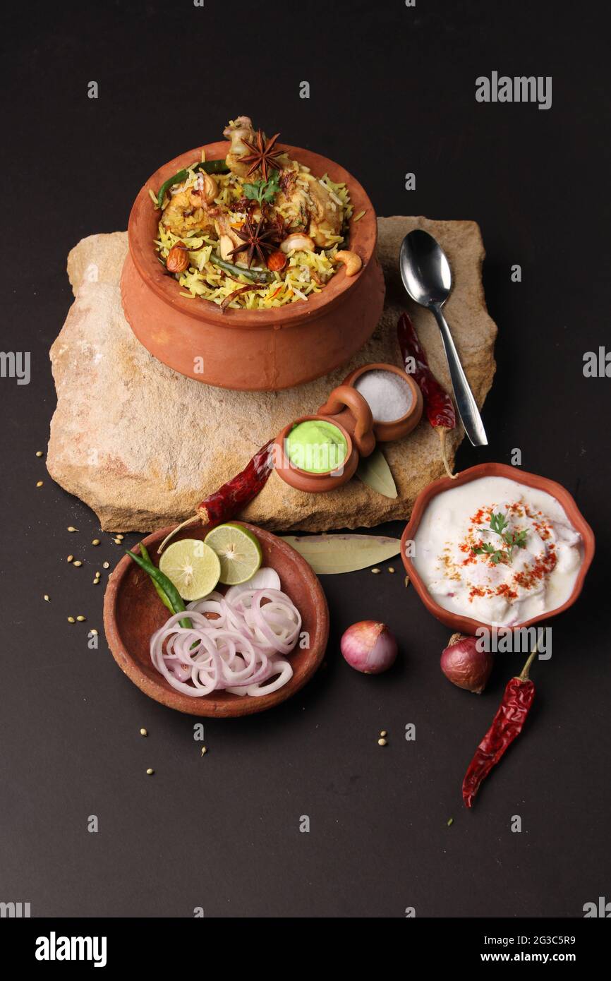 Poulet épicé dum biryani dans un handi traditionnel ou une casserole d'argile. Servi avec raita d'oignon Banque D'Images