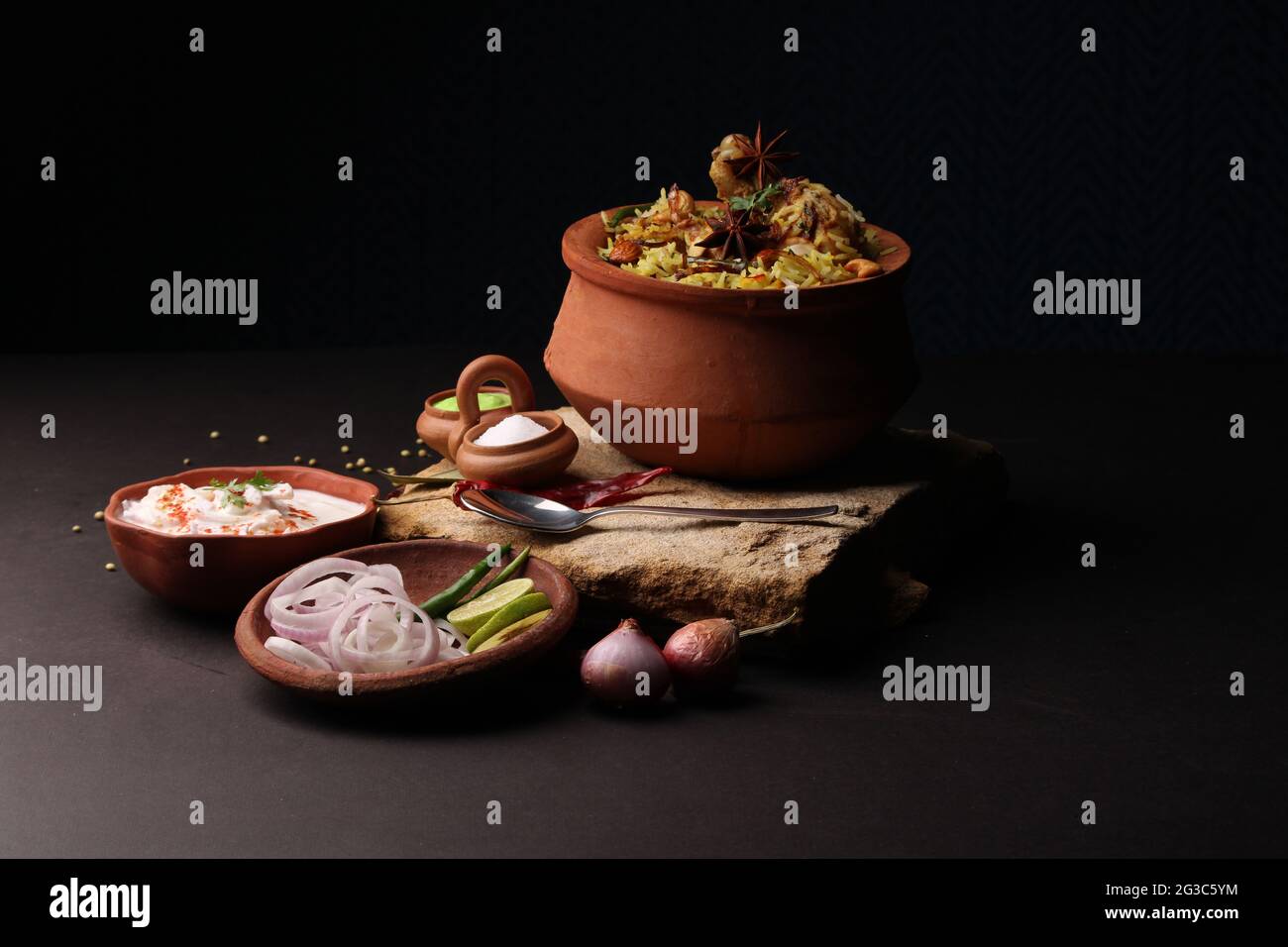 Poulet épicé dum biryani dans un handi traditionnel ou une casserole d'argile. Servi avec raita d'oignon Banque D'Images