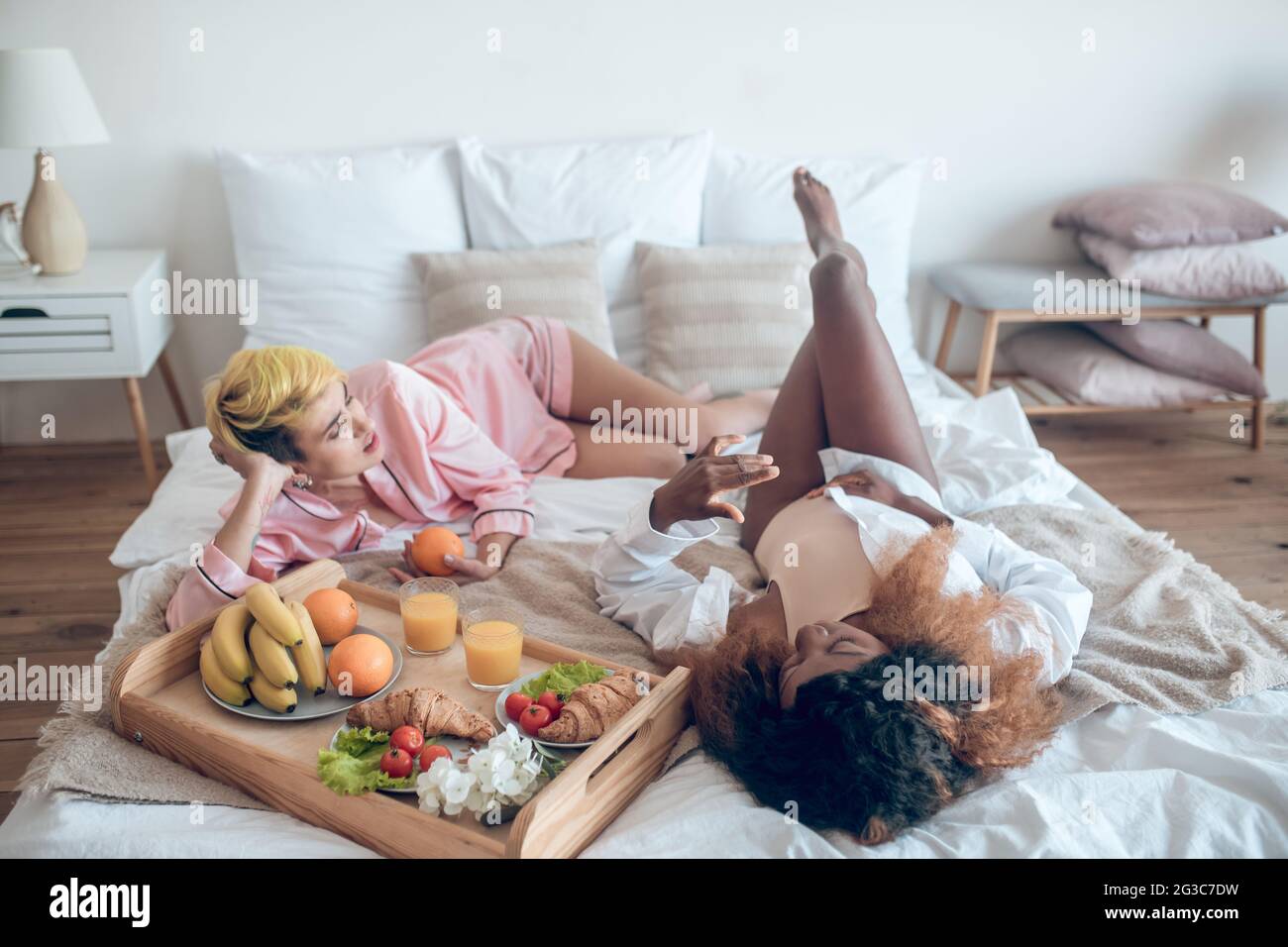 Deux femmes dans des vêtements de couchage couchés sur le lit communiquant Banque D'Images