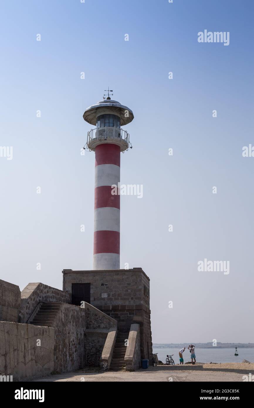 Une vue sur le port avec un grand vieux phare blanc rouge, jetée contre le ciel bleu et la mer Banque D'Images