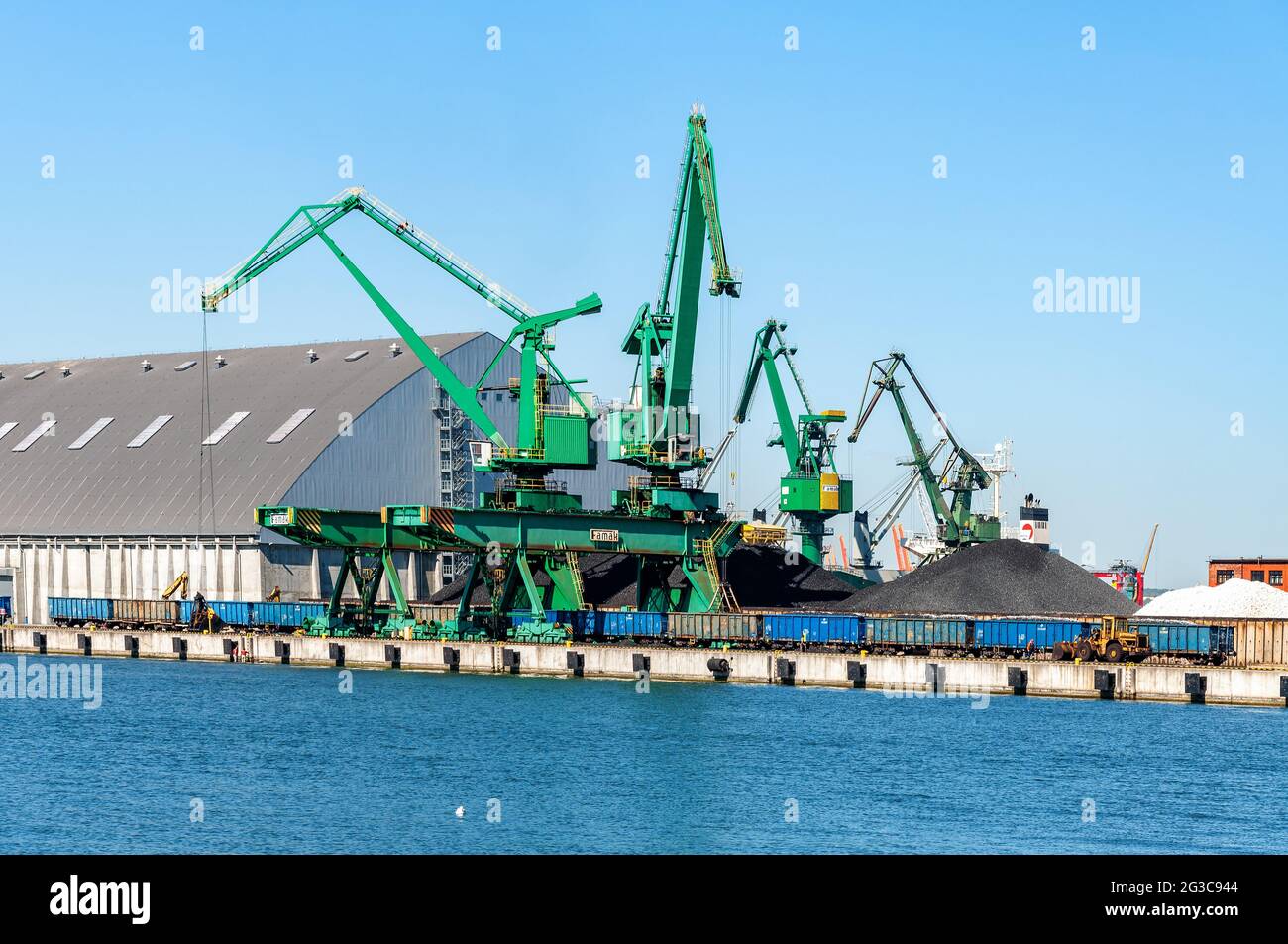 Port de Gdynia en Pologne. Le quai avec des grues portuaires, des trains et des piles de charbon et d'autres marchandises en vrac Banque D'Images