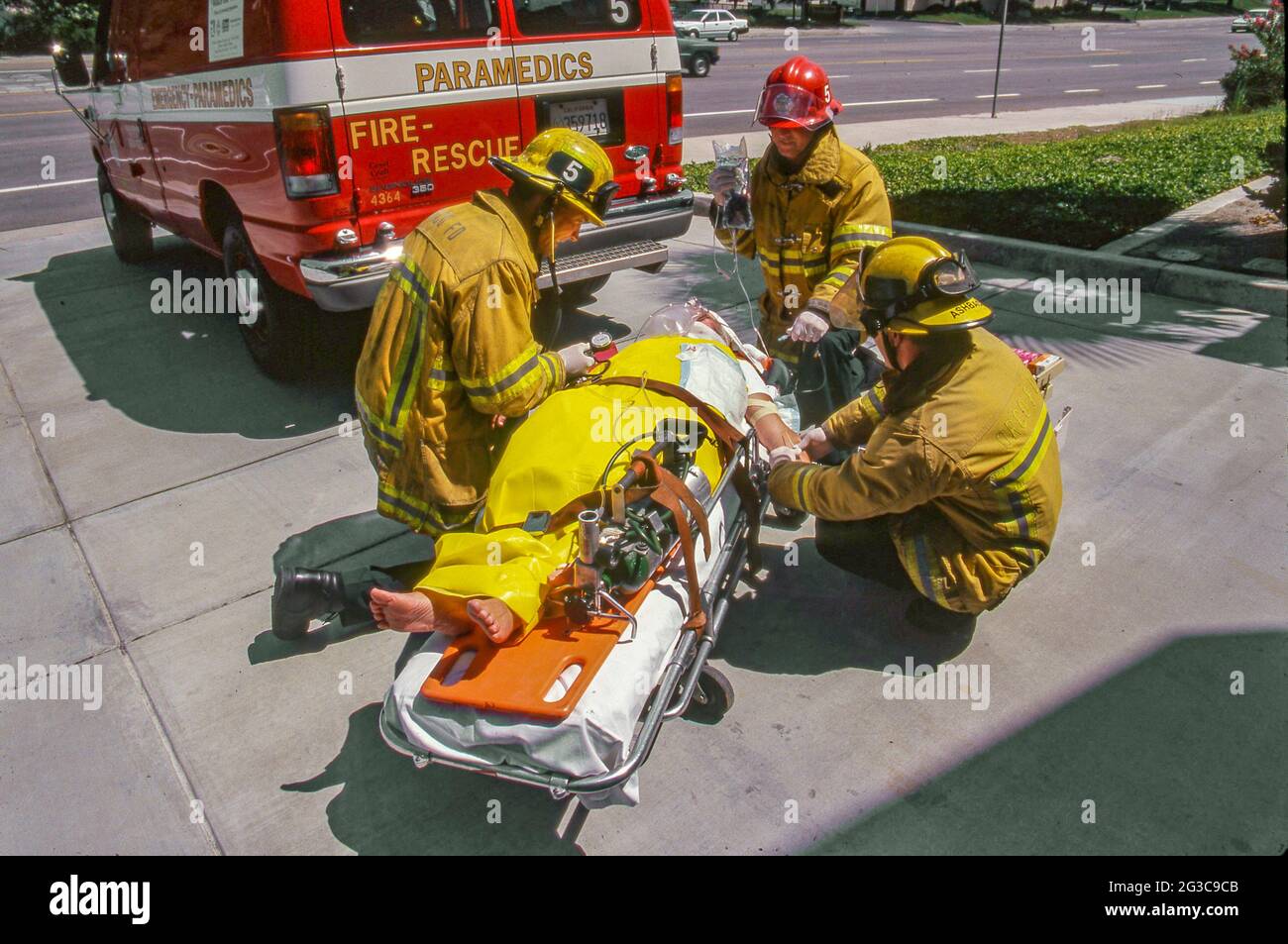 Les techniciens médicaux d'urgence du service des incendies rendent l'aide médicale à une victime d'accident sur un brancard dans la rue de Laguna Niguel, CA. Banque D'Images