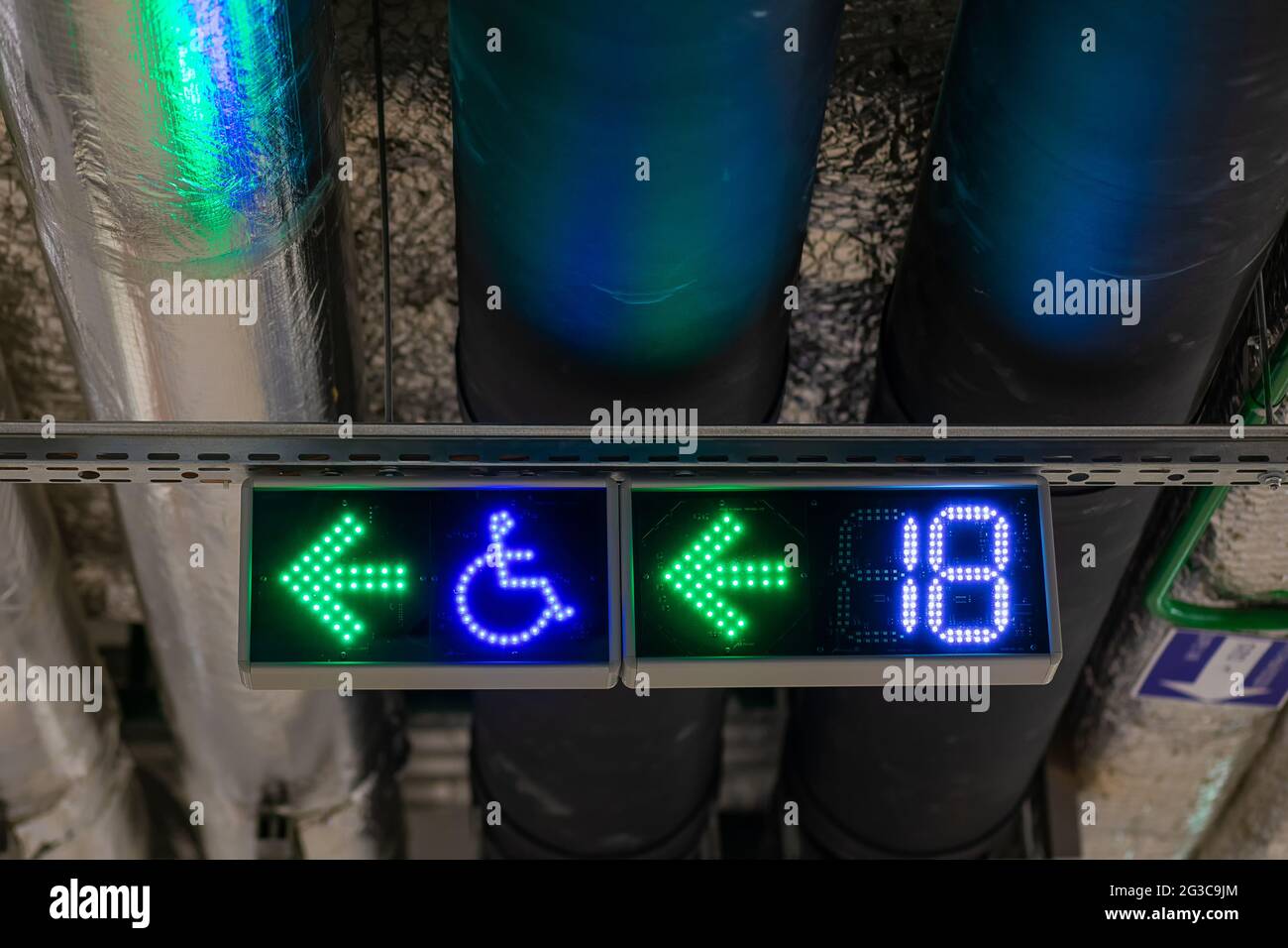 Plomberie sous le plafond du stationnement souterrain avec panneaux de signalisation. Placez une affiche pour les personnes handicapées. Panneau nombre de sièges gratuits. Banque D'Images