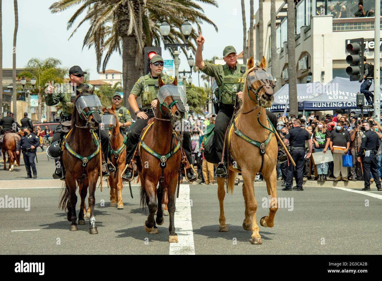 La police montée arrive à Huntington Beach, en Californie, pour le contrôle de la foule lors d'une manifestation politique prévue. Notez les protections oculaires sur les chevaux. Banque D'Images