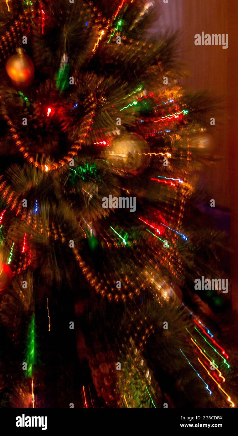 Lumières sur l'arbre de Noël en mise au point avec exposition de deux secondes tout en zoomant pour créer des traînées de lumière abstraites. Banque D'Images