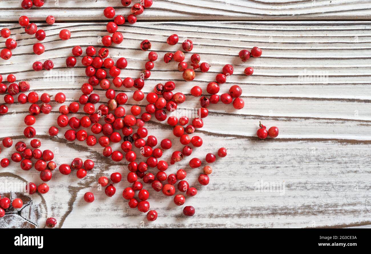 Grains de poivre rouge ou rose éparpillés sur le bureau des tableaux blancs, photo de gros plan du dessus Banque D'Images