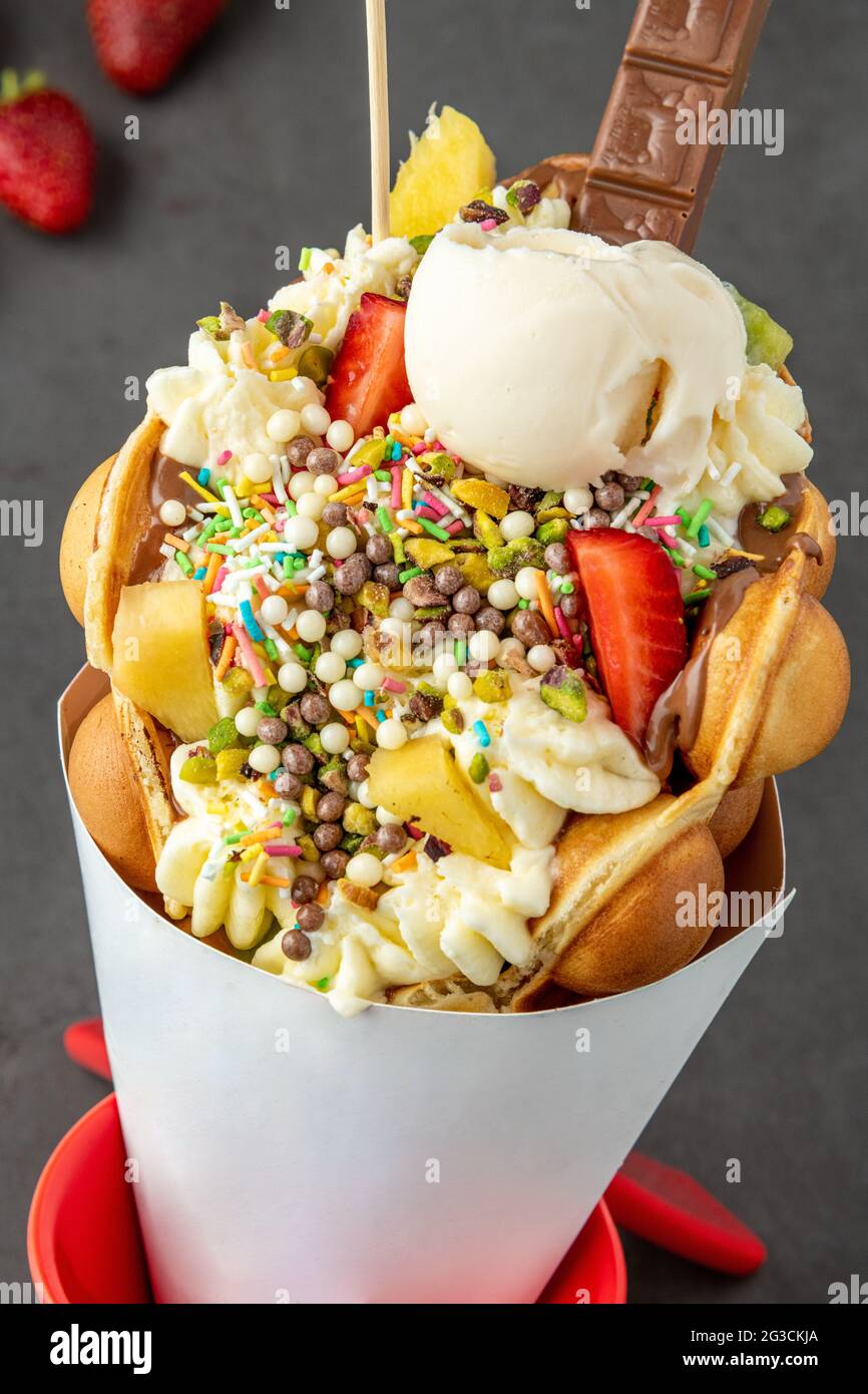 Hong kong ou gaufre à bulles avec crème glacée, fruits, sauce au chocolat et bonbons colorés Banque D'Images