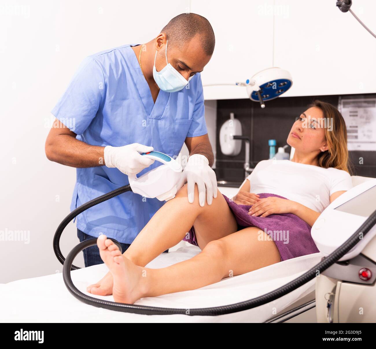 Un cosmétologue de sexe masculin effectue l'épilation au laser pour une  patiente Photo Stock - Alamy
