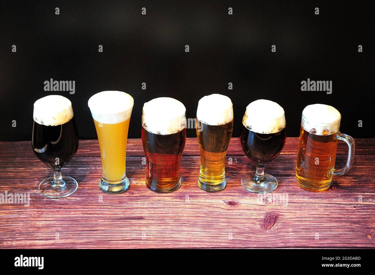 Six verres différents avec différents types de bière sont dans une rangée sur une table en bois. Gros plan. Banque D'Images