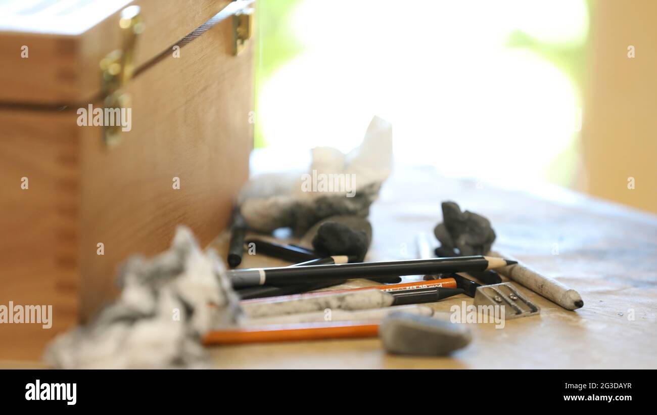 Gros plan sur une variété de supports de dessin utilisés de manière créative par un artiste ou un tiroir. Charbon de bois, crayons, taille-crayon et autres produits artistiques sur un Banque D'Images