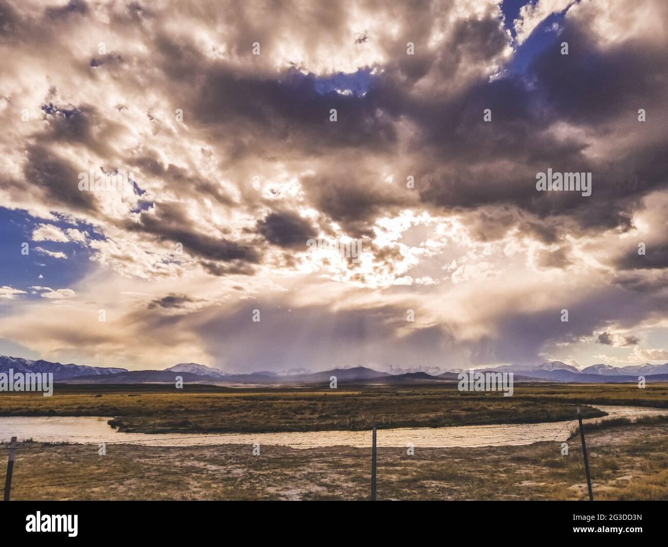 La rivière coule dans une plaine aride au ciel spectaculaire et dans les montagnes Banque D'Images