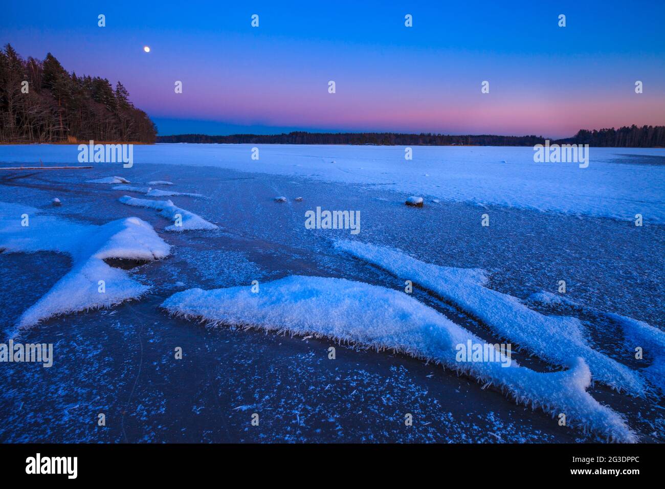 Belle soirée d'hiver avec lune en hausse et ciel coloré à Årvold dans le lac Vansjø, Moss kommune, Østfold, Norvège, Scandinavie. Banque D'Images