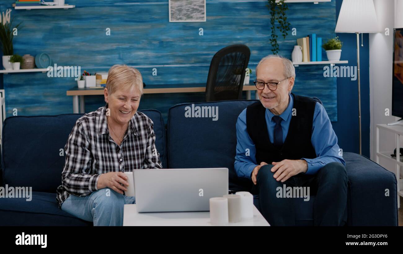 Un couple de personnes âgées ravie au salon avec des neveux sur un ordinateur portable assis sur un canapé. Personne âgée sur Internet en ligne chat technologie vidéo webcam, réunion virtuelle en ligne conférence Banque D'Images