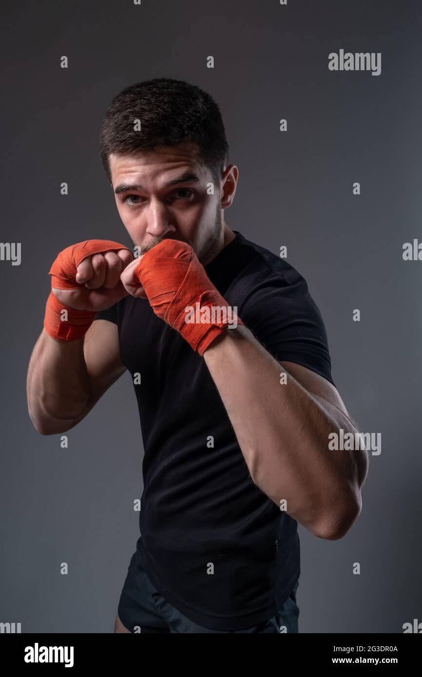 Boxeur jeune avec bandages rouges sur les mains posant dans une position orthodoxe Banque D'Images