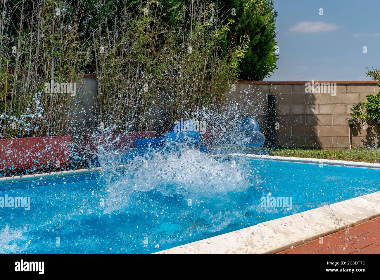 Une énorme éclaboussure d'eau est créée par la plongée de balle de canon dans une piscine Banque D'Images