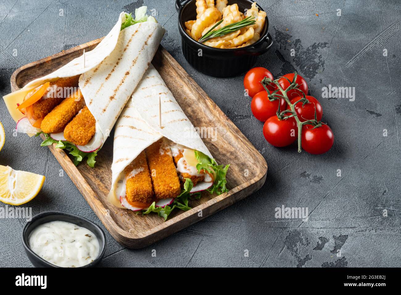 Les doigts de poisson roulent et la sauce tartre ensemble, sur plateau en bois, sur fond gris , avec espace de copie et espace pour le texte Banque D'Images