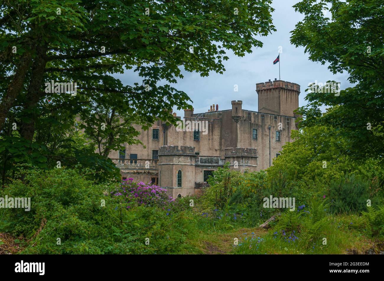 Vue sur le château de Dunvegan qui émerge au milieu des bois. Concept: Voyage en Ecosse, bâtiments historiques écossais, lieux de charme et mys Banque D'Images