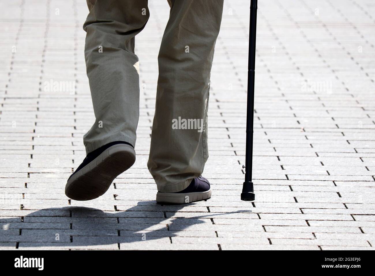 Homme marchant avec une canne en bas de la rue. Notion de vieillesse, maladies de la colonne vertébrale ou maladie articulaire, personnes âgées Banque D'Images