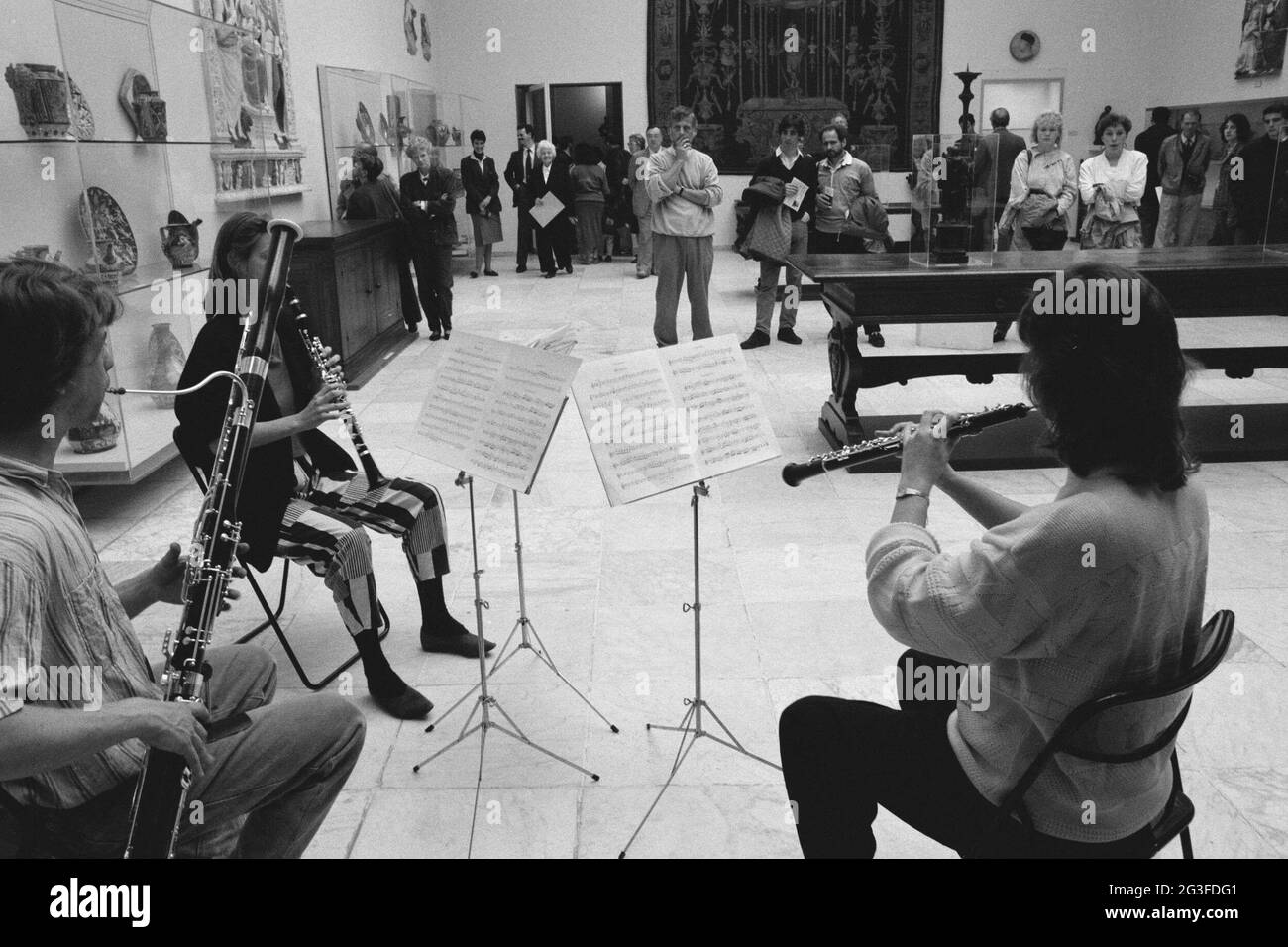 Deux femmes assises et un homme jouant des instruments de vent pendant les montres publiques; week-end de musique. . Banque D'Images