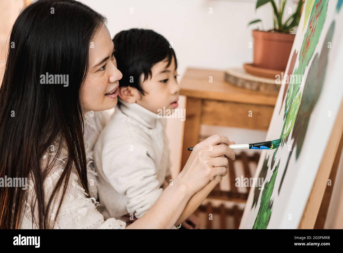 Enfant asiatique et maman peinture sur toile pendant les cours d'art à la maison - Focus sur la femme oeil Banque D'Images