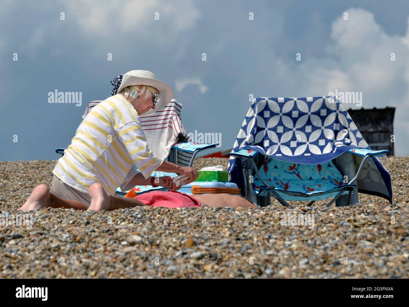 femme plus âgée appliquant de l'huile de bronzage au mari sur la plage de dunwich suffolk angleterre Banque D'Images