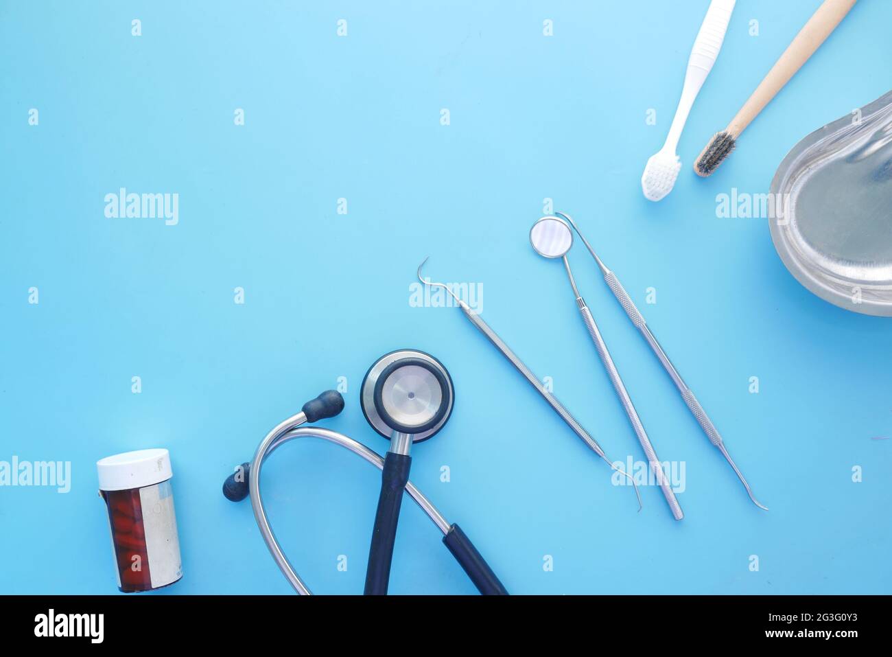 matériel dentaire , stéthoscope et récipient à pilules sur bleu Banque D'Images