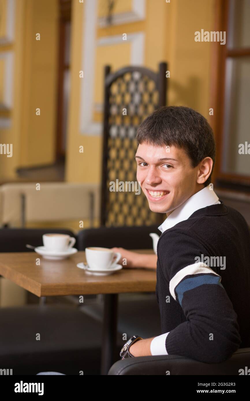 Jeune homme sur table avec tasse de café Banque D'Images